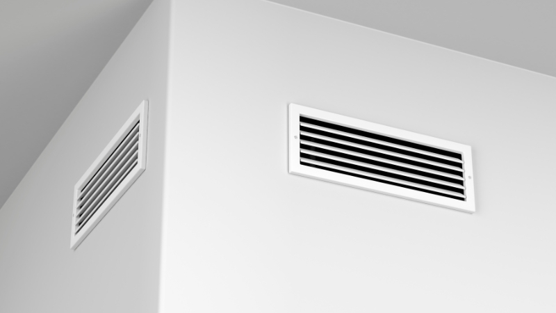Dve bele ventilacione rešetke ugrađene na zidu
