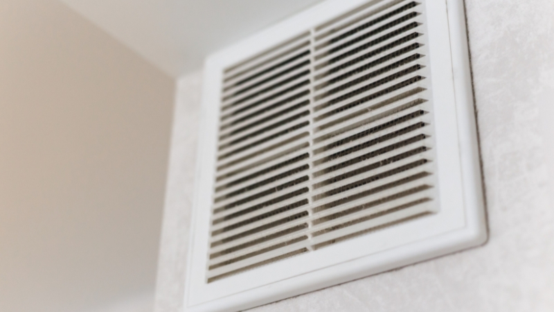 Bela ventilaciona rešetka ugrađena na zidu prostorije