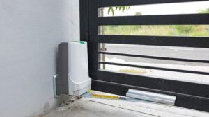 Motor za krilnu kapiju montiran na betonskoj podlozi, povezan sa metalnim krilom preko poluge